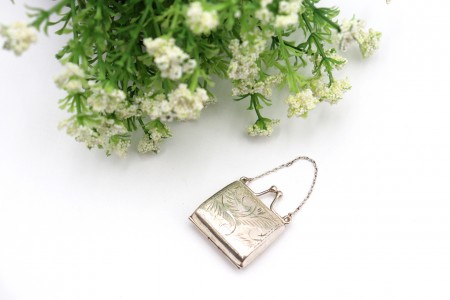 Caixa de comprimidos em prata em forma de mala com gravados e corrente